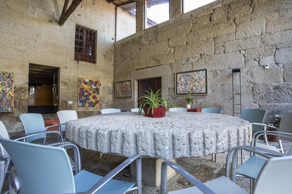 Une pièce aux murs de pierre, avec une table ronde, des chaises et des œuvres d’art accrochées aux murs.