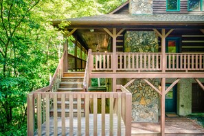 Eine Holztreppe führt zu einem Steinhaus mit einem Balkon.