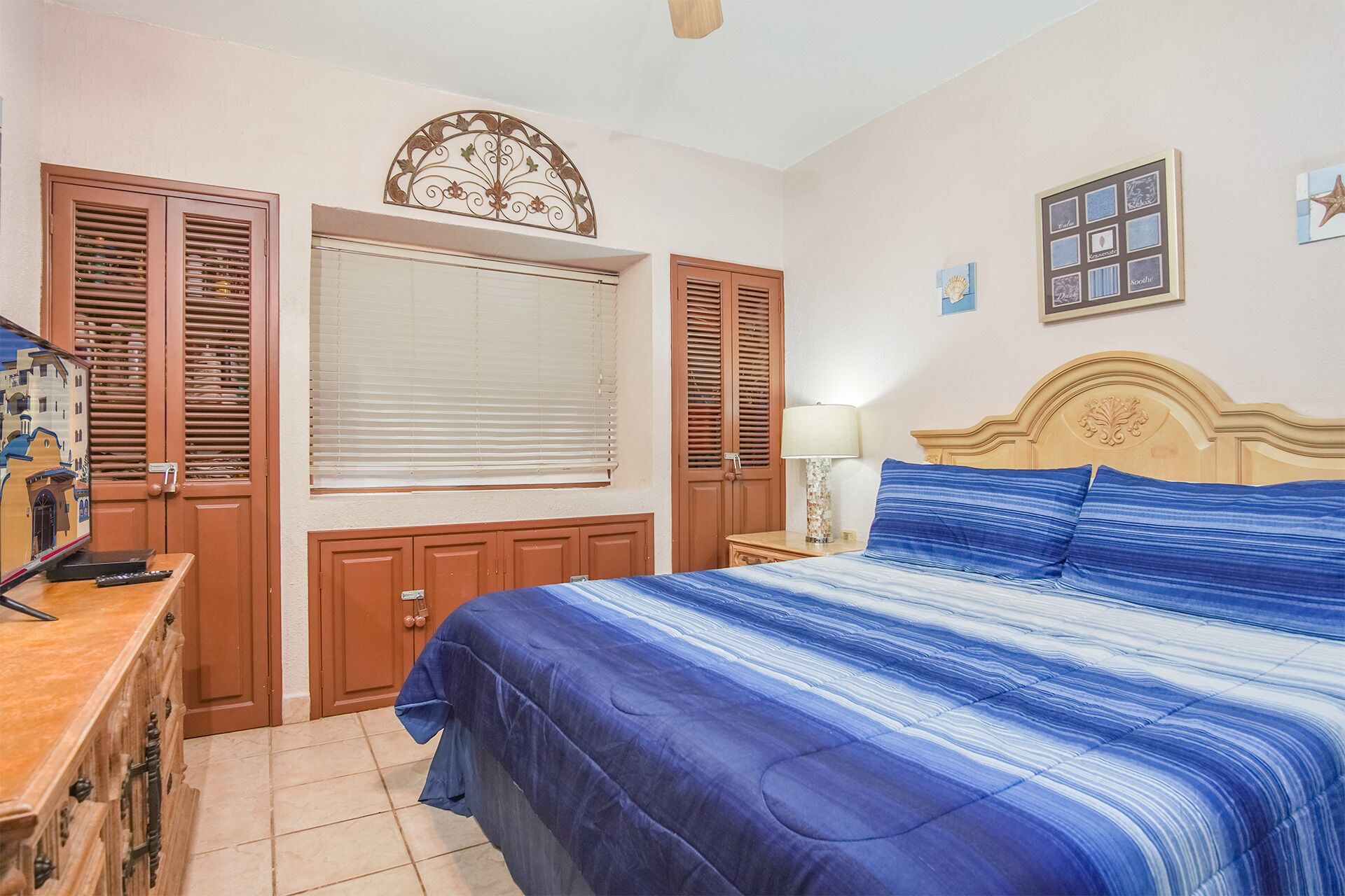 A bedroom with a bed, wooden wardrobe, and a window with blinds.