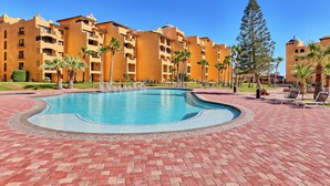 A hotel with a swimming pool, palm trees, and a clear blue sky. - Princesa Resort B-201 Slow M'Ocean Cottage Ocean View Private Condo (Puerto Penasco)