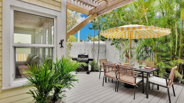 An outdoor patio with a dining table, chairs, and a grill.