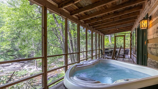 Ein Whirlpool auf einer Holzterrasse mit Blick auf bewaldetes Gelände.
