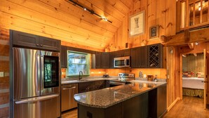 Eine moderne Küche mit Edelstahlgeräten, Granit Arbeitsplatten und Holzvertäfelung.