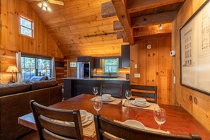 Un intérieur en bois comprenant une table à manger pour quatre personnes, un canapé et un coin cuisine.