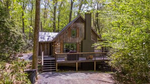 Une cabane rustique dotée d’une terrasse en bois, d’une cheminée et d’un porche avec une balustrade.