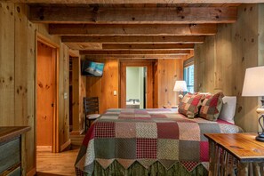 Une pièce chaleureuse en bois, avec un grand lit, une télévision et un bureau en bois.
