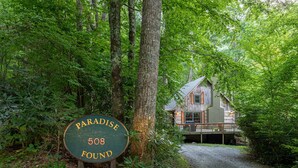 Ein Holzschild mit der Aufschrift 'Paradise 508' und eine rustikale Holzhütte mit Veranda.