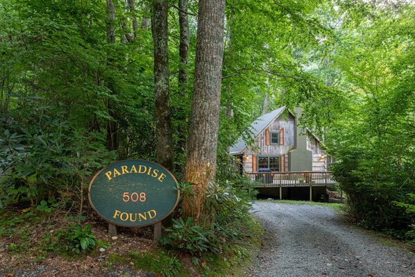 Un panneau en bois portant l’inscription « Paradise 508 » et une cabane rustique dotée d’un porche abrité.