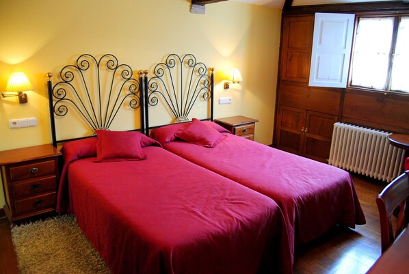 A double bed with a metal headboard, two bedside tables, a wooden wardrobe, and a radiator. - Santo Grial (Santiago de Compostela)