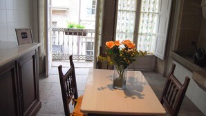 Ein Essbereich mit Tisch, Stühlen, einer Vase mit Blumen und Blick auf den Balkon.
