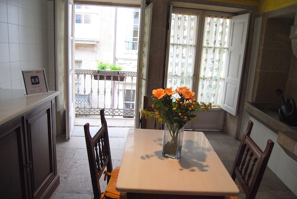 Ein Essbereich mit Tisch, Stühlen, einer Vase mit Blumen und Blick auf den Balkon.