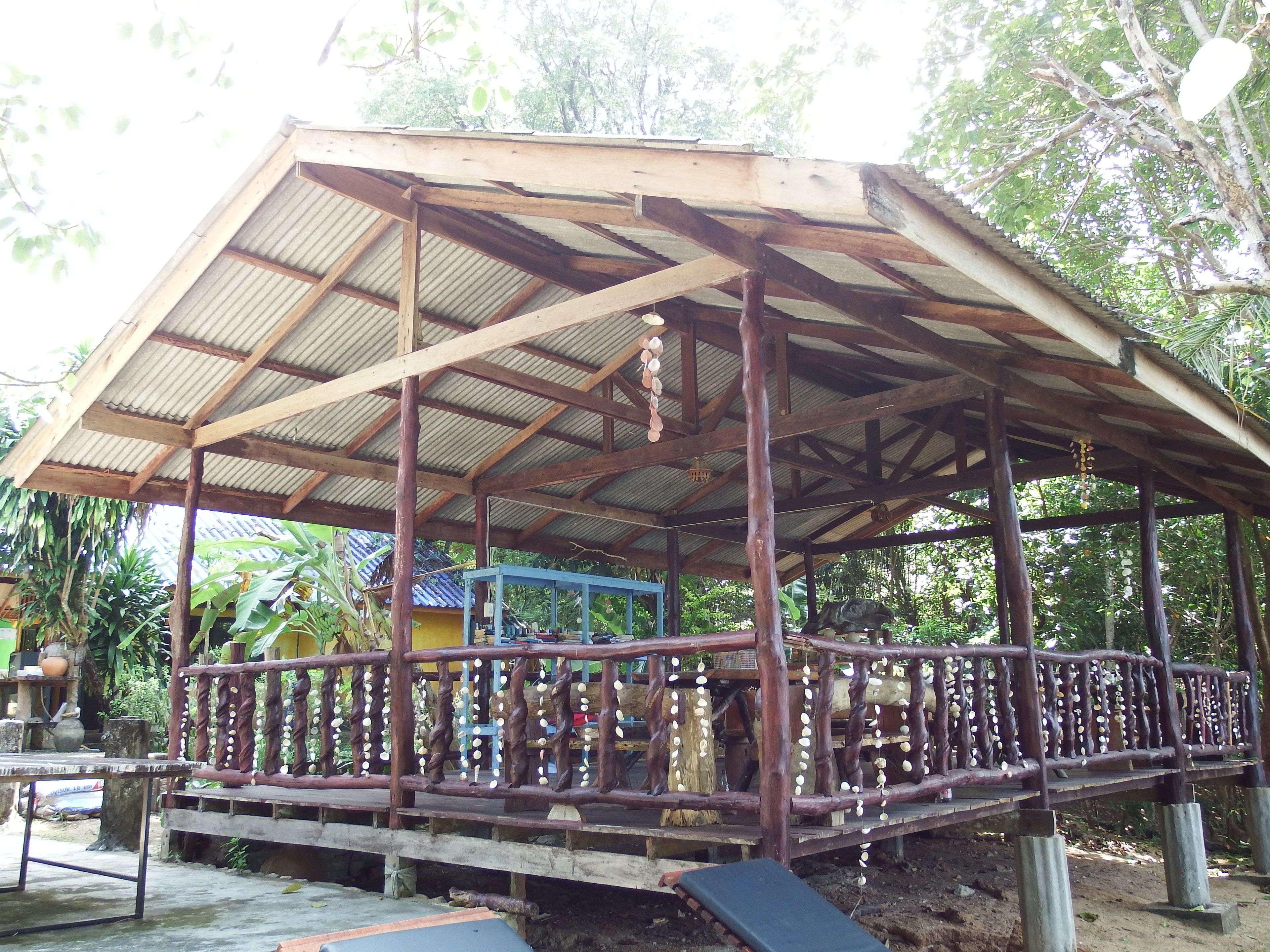 Un espacio al aire libre cubierto con estructura de madera, una banca y una mesa.