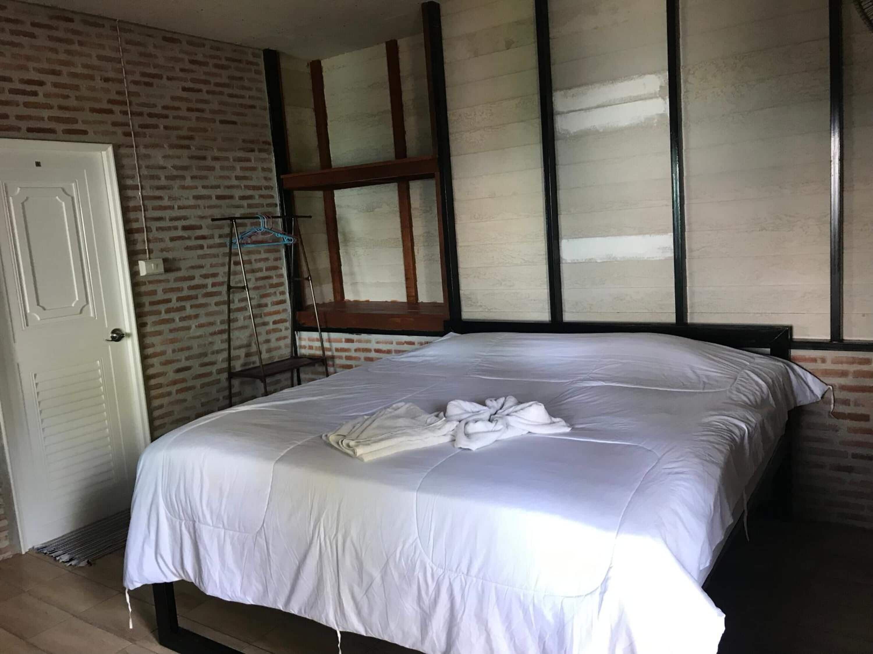 A bedroom with a bed, a window, and a brick wall.
