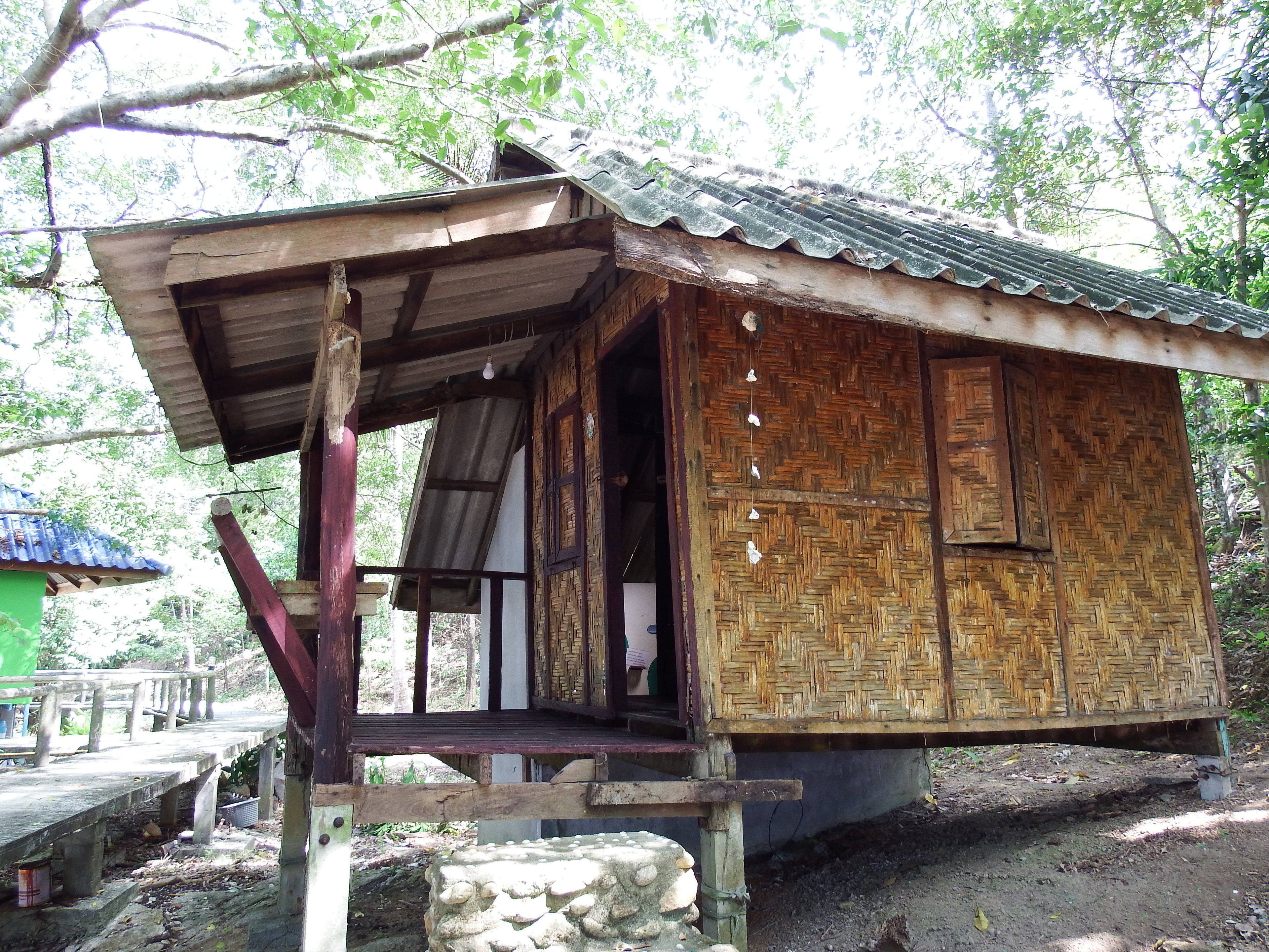 A rustic wooden structure with a corrugated metal roof, a wooden door, and a small porch area.