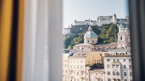 Vue d’un château historique perché sur une colline, avec un paysage urbain en premier plan.