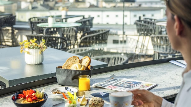 Un coin repas avec une table mise pour le petit-déjeuner, comprenant des toasts, des fruits et un journal.