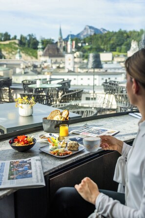 Ein Essbereich mit gedecktem Tisch für das Frühstück, darunter Toast, Obst und eine Zeitung.