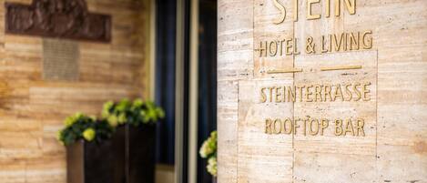 A wooden facade with a sign for "STEIN HOTEL & LIVING" and "STEIN TERRASSE ROOFTOP BAR".