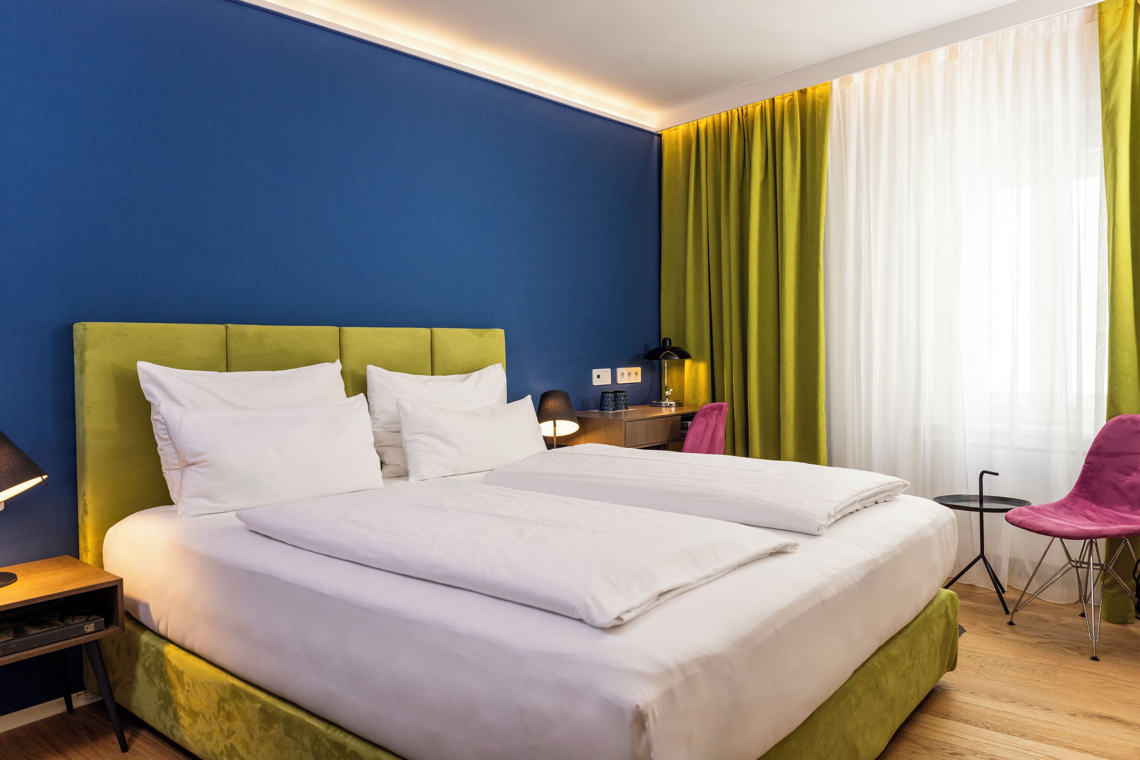 A hotel room with a large bed, a desk, and a chair.