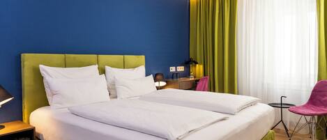 A hotel room with a large bed, a desk, and a chair.