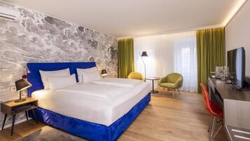 Una habitación de hotel moderna con una cama grande, un escritorio, una silla y un televisor.
