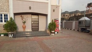 A building with a reception area, potted plants, and a signboard. - Jesuit Continental Suites (Abuja)