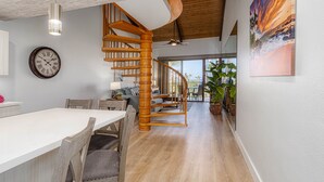 Uma sala de jantar ampla com uma escada de madeira que dá acesso a um andar superior.