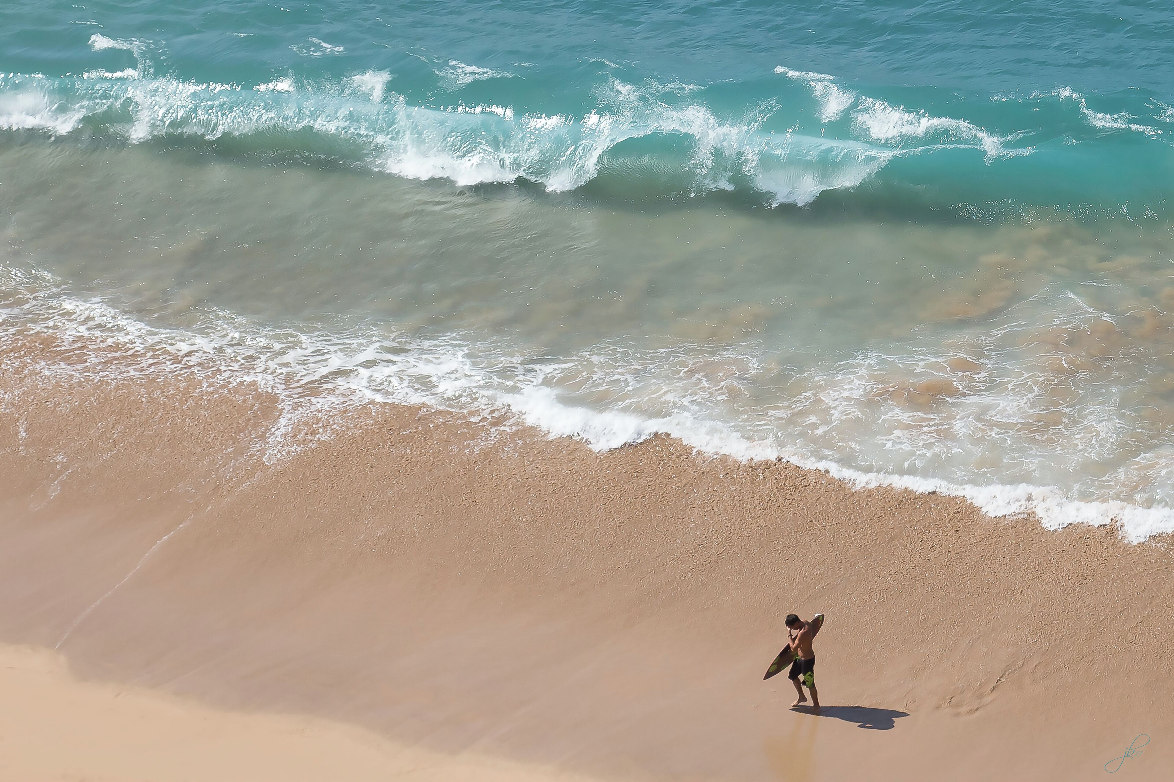 Une plage où l’on voit une personne debout près du bord de l’eau.