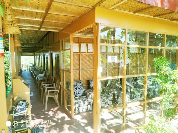 Un espacio de estar al aire libre cubierto, con bancos de madera y techo de paja.