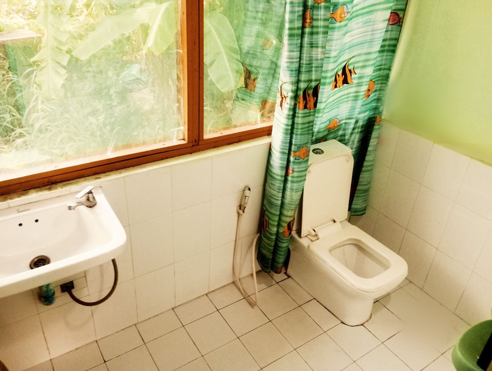 Une salle de bain avec des toilettes, un lavabo et une fenêtre.