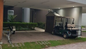 Un edificio moderno con un'area di parcheggio coperta, un carrello da golf e un piccolo deposito.