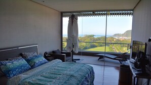 Una camera da letto con un letto grande, un'area salotto vista e un balcone panoramico.