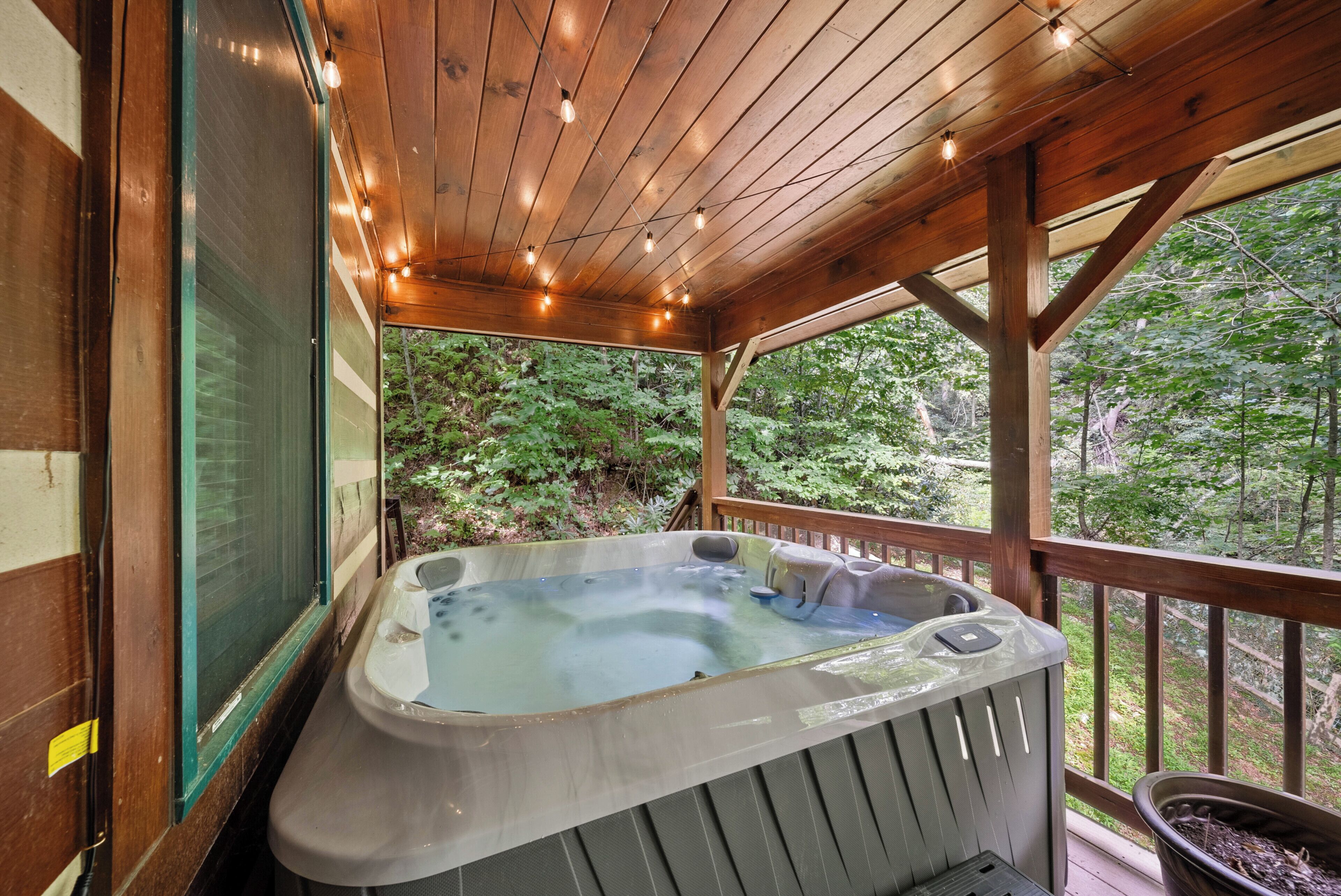 A hot tub on a wooden deck with a view of a forest.