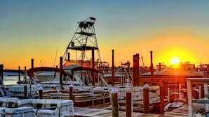 A marina at sunset with boats docked, wooden walkways, and a large crane structure. - (519) Paradise Found in this Stylish, high end condo. Stunning Views! (Destin)
