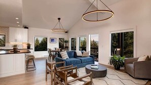 A spacious living area with a blue sofa, wooden chairs, a coffee table, and pendant lighting. - Abode at Rendezvous, private entrance, large deck (Teton Village)