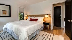A bedroom with a large bed, bedside lamps, a wooden headboard, a nightstand, and a door. - Abode at Rendezvous, private entrance, large deck (Teton Village)