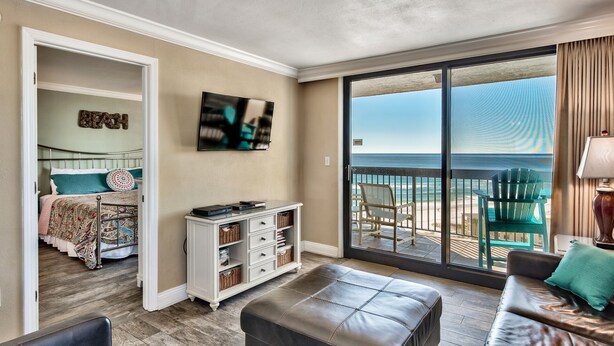 A room with a bed, a TV, a desk, and a view of the beach. - 2 BR Condo! Awesome Views! 14th floor!  Resort on Sand! Heart of Destin! (Destin)