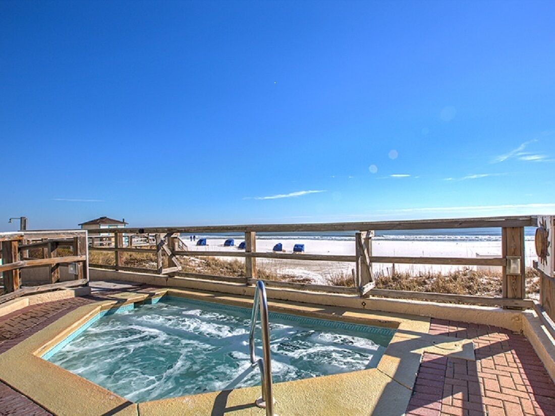 Een hottub met een houten terras en uitzicht op het strand.