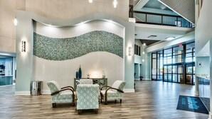 A spacious lobby with a curved wall mosaic, a reception desk, and a seating area with patterned chairs. - 2 BR Condo! Awesome Views! 14th floor!  Resort on Sand! Heart of Destin! (Destin)