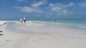 Een strand met wit zand en helder turquoise water.