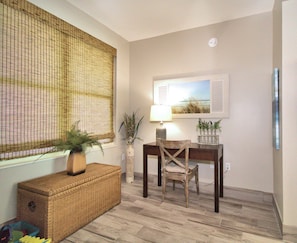 A room with a dining table, chairs, a wicker chest, a potted plant, and a window with a bamboo blind. - 1703 - 3 Bedroom 3 Bath. Master Bedroom on the Gulf (Panama City Beach)