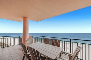 A covered outdoor area with a table and chairs, overlooking a beach and ocean.
