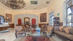 Eine großzügige Lobby mit einem runden Glastisch, verzierten Stühlen, einer Couch und einem Chandelier.