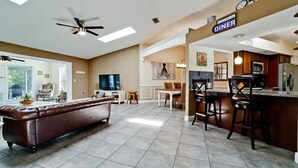 A modern kitchen with a dining area, a bar, and a television.