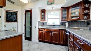 A kitchen with wooden cabinets, a granite countertop, and a tiled backsplash.