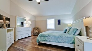 Une chambre à coucher avec un lit, une commode, une chaise et une fenêtre.