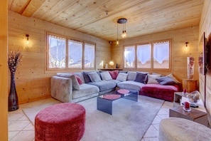 A cozy living room with a sectional sofa, a glass coffee table, and a red ottoman.