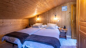 Una camera da letto accogliente con rivestimenti in legno, due letti, comodini e luci a parete.