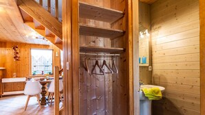 Un interno in legno con zona pranzo, un armadio in legno con spazio per appendere e un bagno con lavabo e asciugamani.