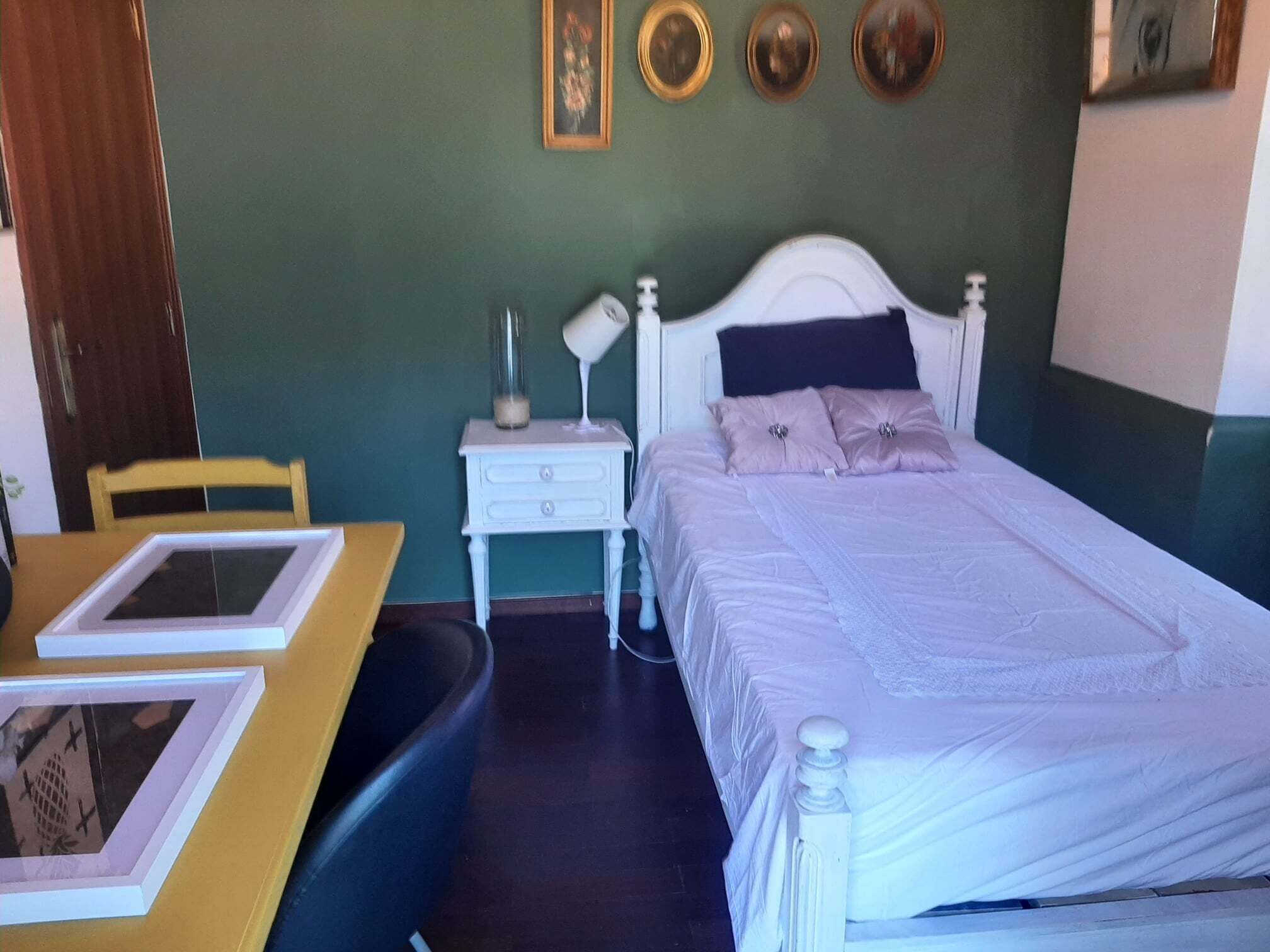 A bedroom with a bed, bedside table, lamp, and a chair.